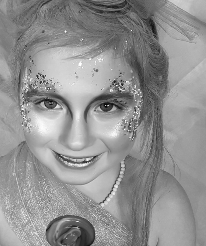 Faded background image of a young girl with glittery makeup smiling at the camera.